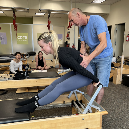 a man helping a woman to do a pilates exercise