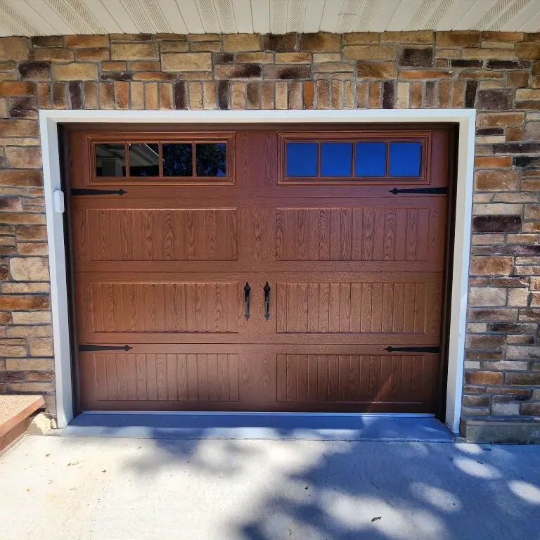 image placeholder A closed brown garage door with four small rectangular windows at the top, set in a brick exterior wall by West County Garage Door Service.